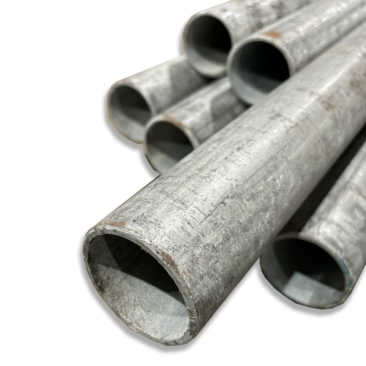 Un conjunto de tubos galvanizados dispuestos en ángulo. Los tubos son de un color metálico brillante y tienen extremos cortados, mostrando su interior hueco. La imagen presenta un enfoque en la textura y el acabado de los tubos.