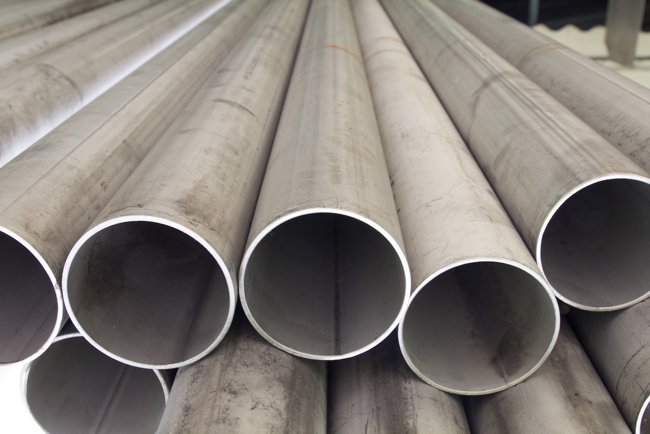 Tubería galvanizada de MMTubería dispuesta en un entorno industrial. Se ve un conjunto de tubos galvanizados apilados en un ángulo, con un acabado liso y color gris.